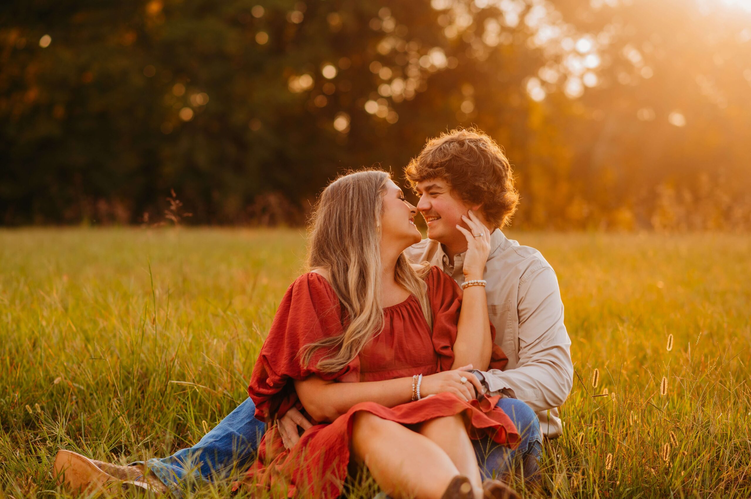 woman caressing her fiance's face as they sit in a field