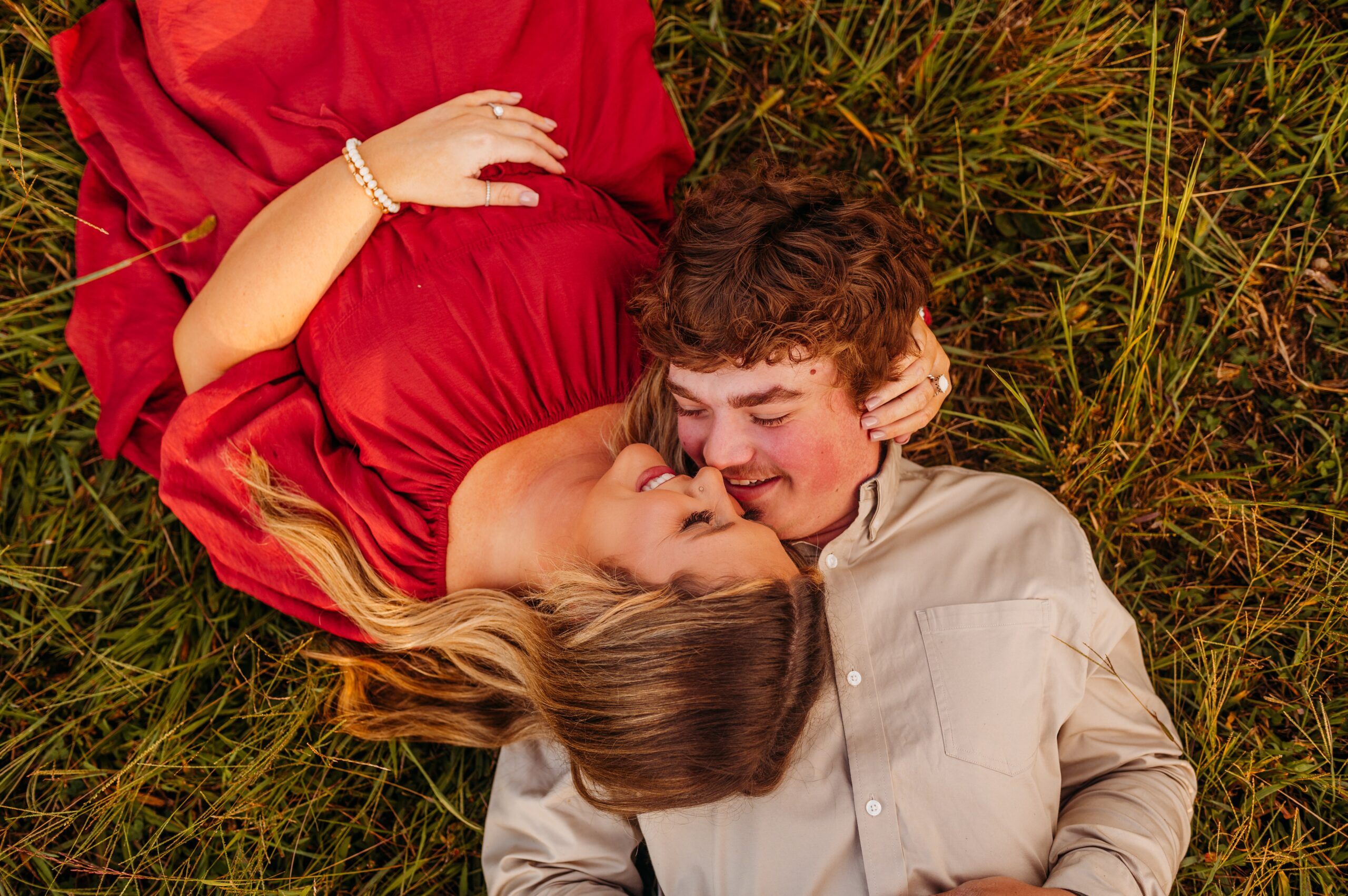 man and woman laying down in a field and about to kiss