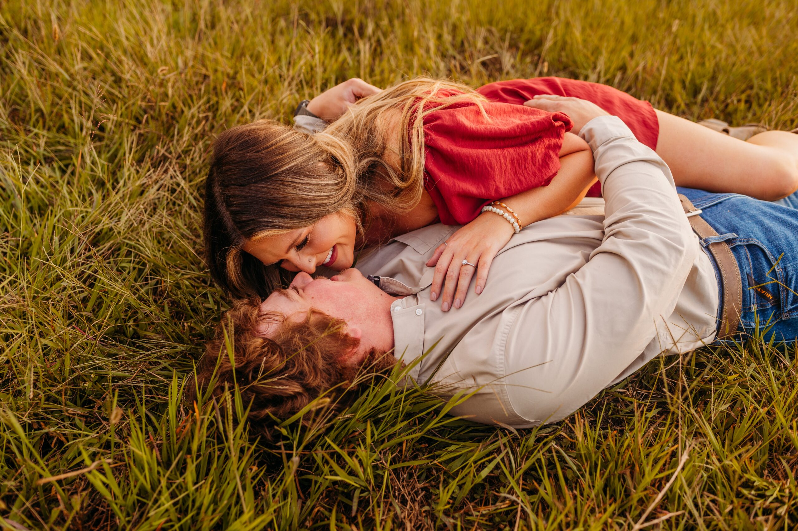 woman laying on her fiancee in a field