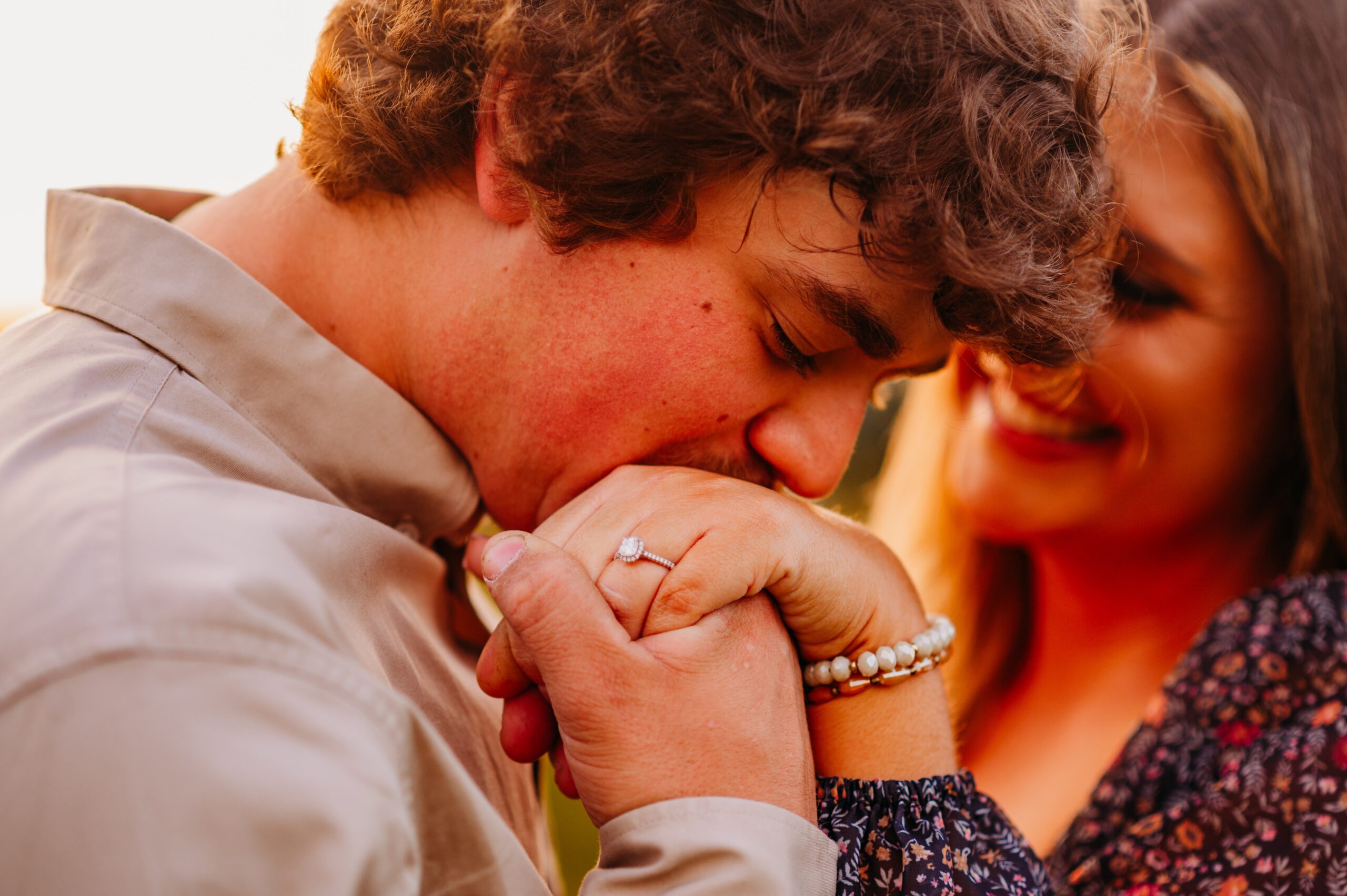 man kissing his fiancee's hand as she shows off his engagement ring