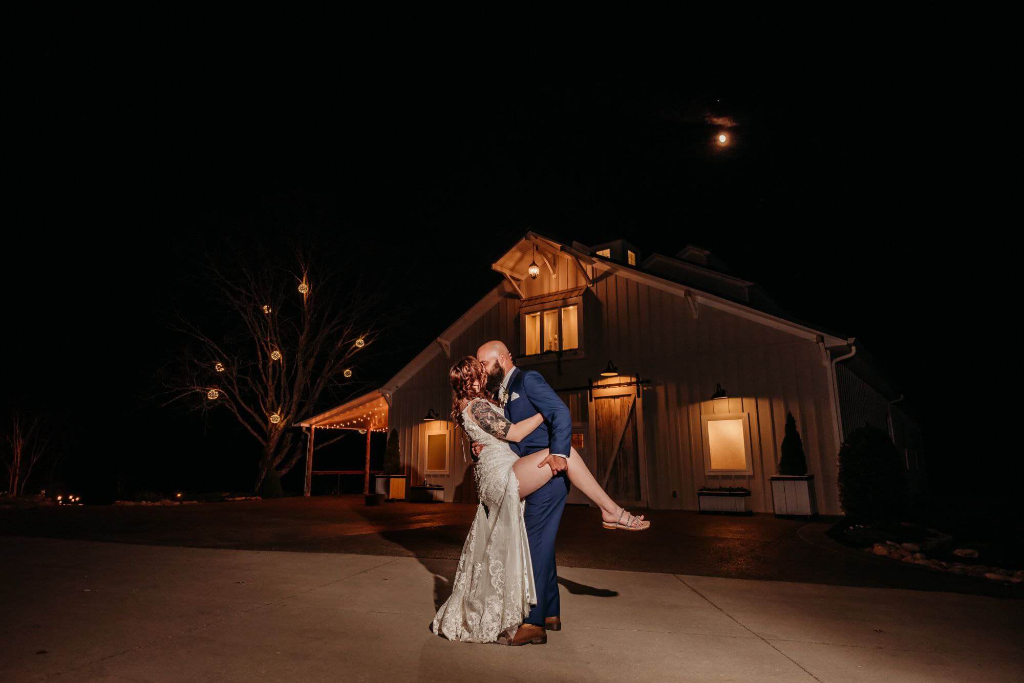 groom dipping and kissing his bride in Athens, TN in front of a glowing barn at night