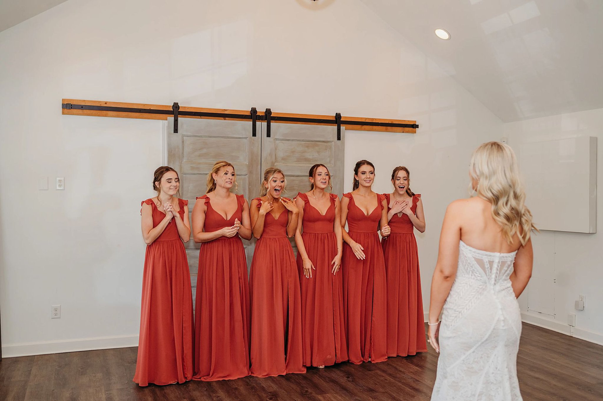 bridesmaids in maroon dresses shocked at how pretty the bride is in front of them