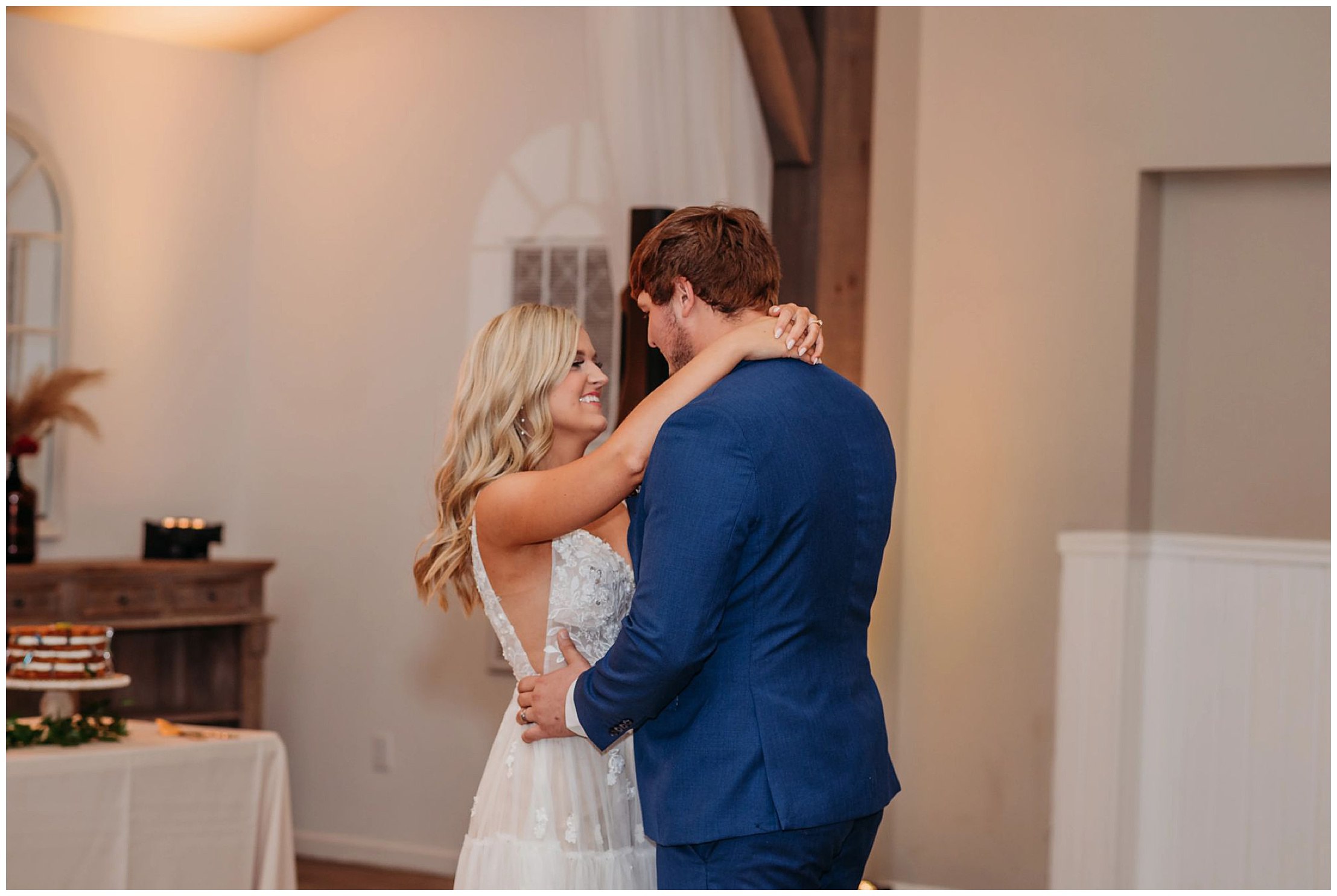 bride and groom slow dancing and smiling indoors with white walls