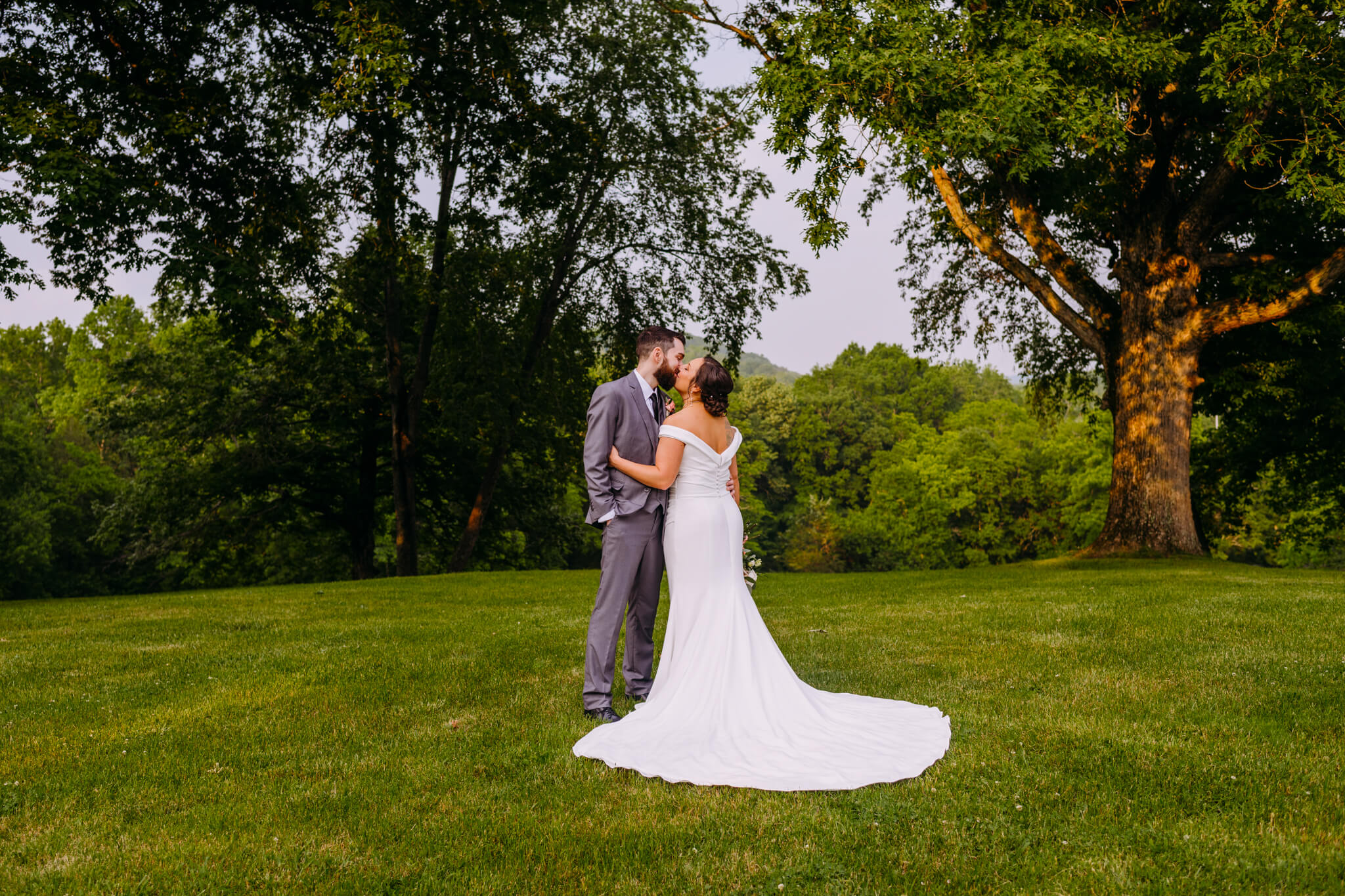 photo of a bride and groom hugging with tress in the background