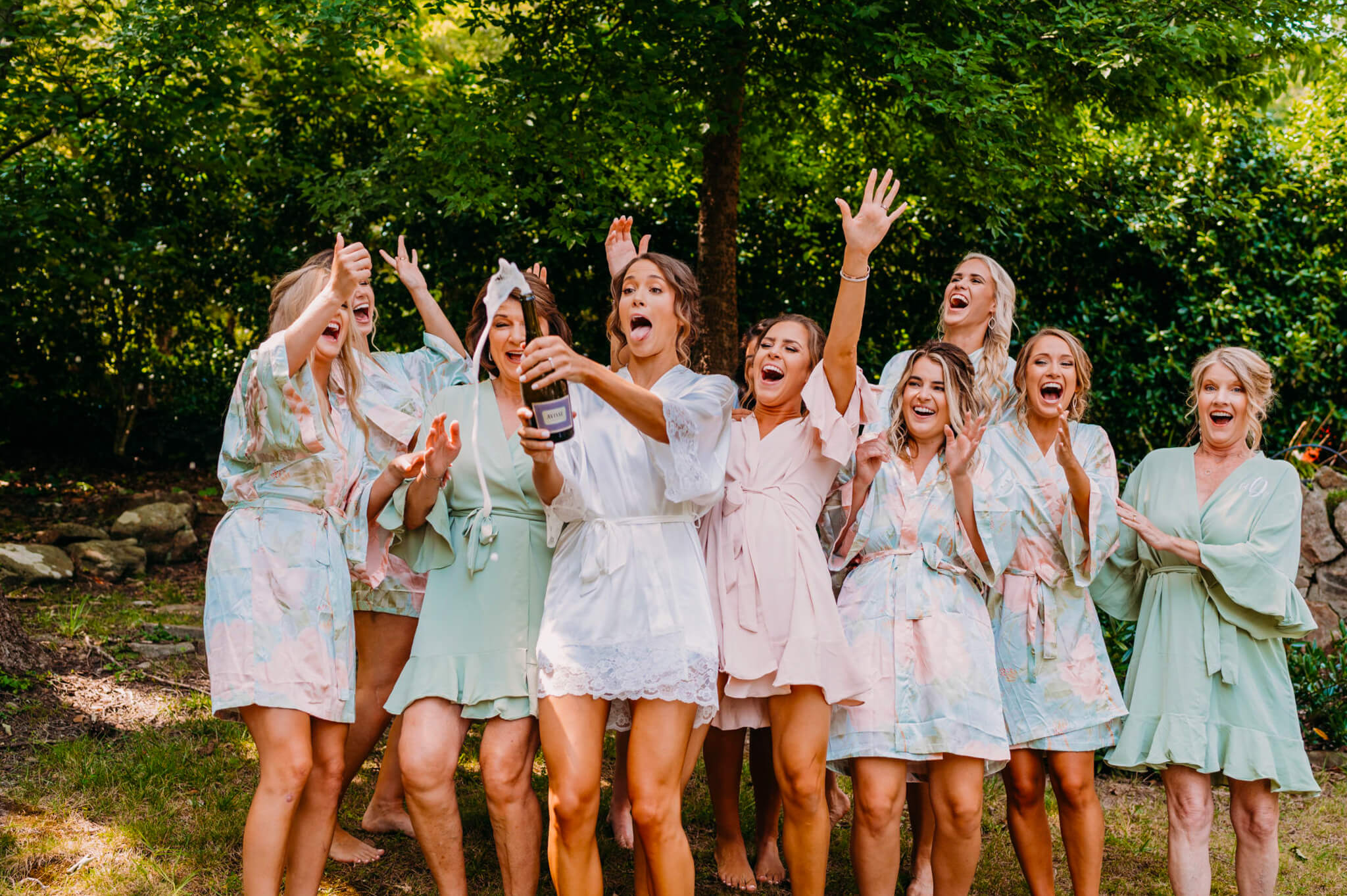 photo of bride popping champagne and sticking her tongue out while surrounded by laughing bridesmaids in robes at The Grandview venue